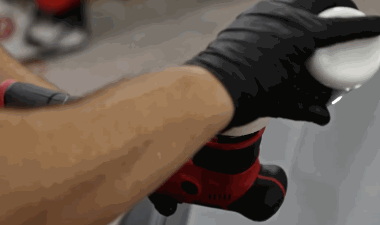 A gloved technician uses a dual-action polisher on a gray vehicle panel to begin surface correction before ceramic coating.